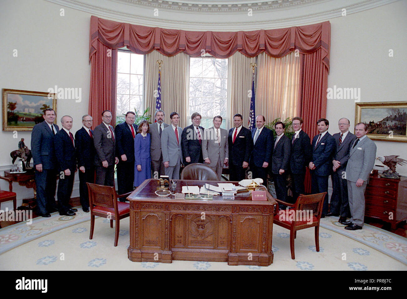 3-24-1988 President Reagan during a photo opportunity with senior staff members of the National Security Council NSC staff  John Negroponte, Colin Powell, Paul Stevens, William Cockell, Herman Cohen, Stephen Danzansky, Robert Dean, Fritz Ermarth, Alison Fortier, D Barry Kelly, James Kelly, Robert Linhard, Robert Oakley, Peter Rodman, Nicholas Rostow and Jose Sorzano in the Oval Office Stock Photo