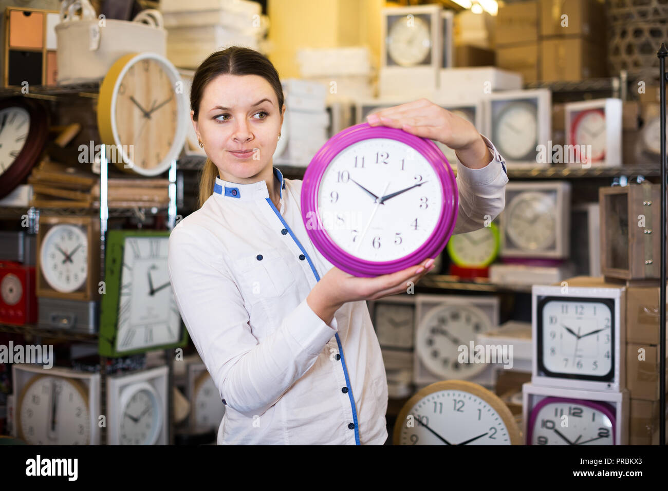 Smiling purchaser is standing with wall clock in the shop Stock Photo