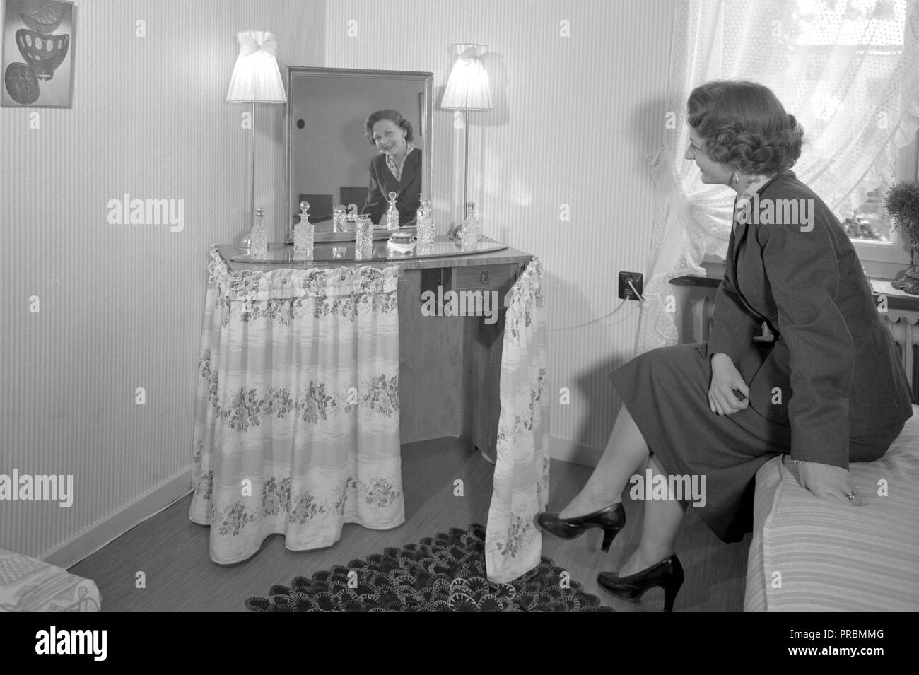 1950s women at home. A woman in her bedroom at home showing the makeup table. A furniture designed to be functional for makeup and hairstyling.  Sweden 1954.  Ref 2797 Stock Photo