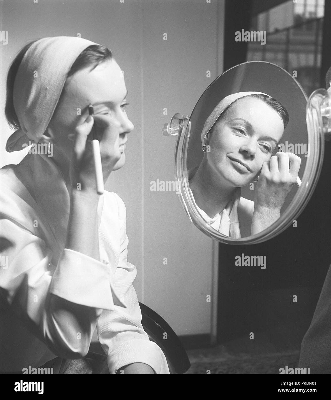 Woman in the 1950s. A young brown haired woman is applying makeup in front of a mirror. Pictures actress Anita Björk, 1923-2012.  Sweden 1950. Photo Kristoffersson ref  BA3-3 Stock Photo