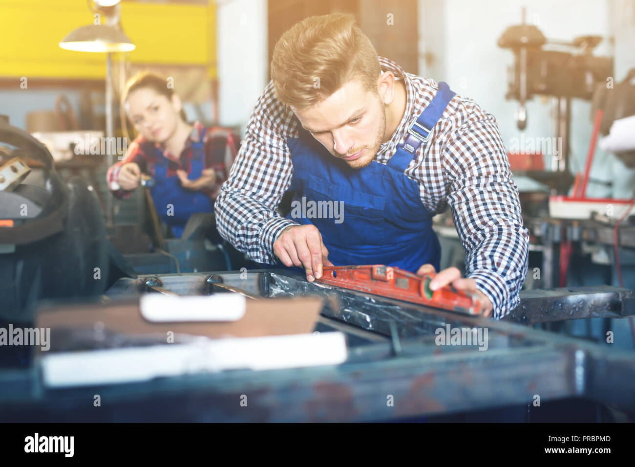Young man is working with level on his workplace in workshop Stock Photo