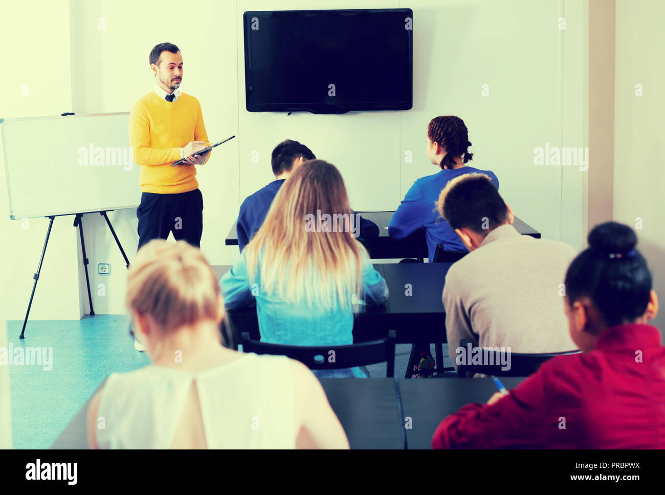 Teacher is monitoring students during revision work in class. Stock Photo