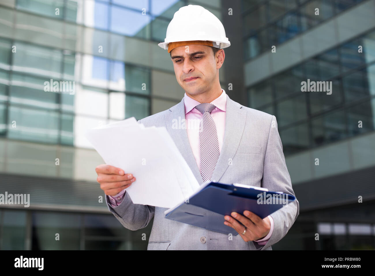 Businessman holding folder with documents and attentively reading Stock Photo