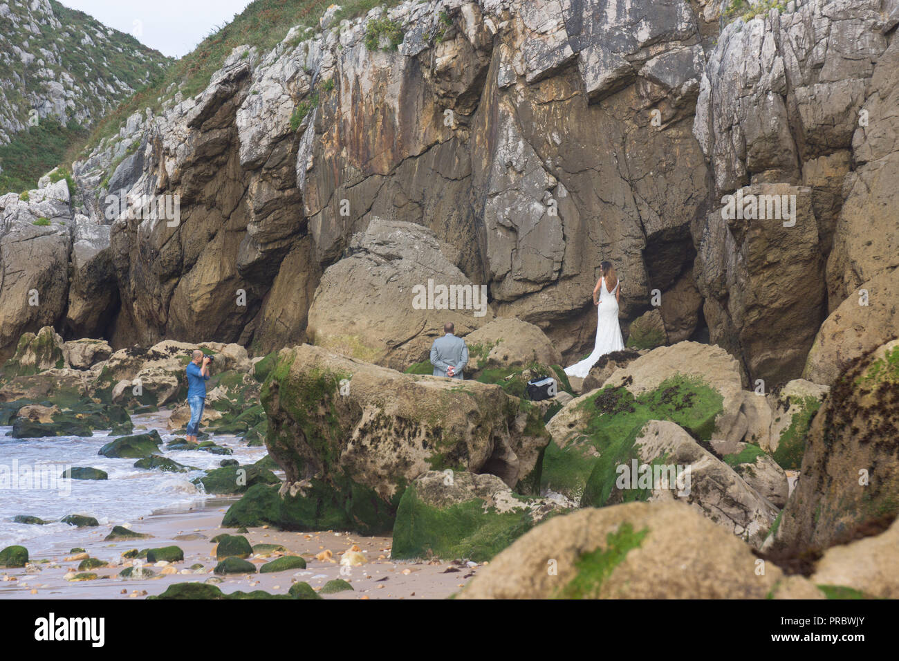 Photo shoot of bride in wedding dress by some cliffs on a beach at the seaside Stock Photo