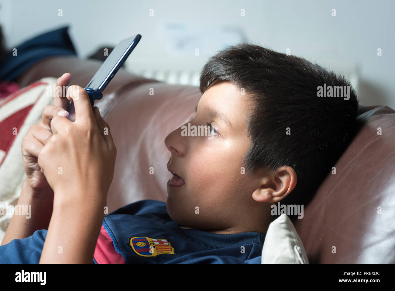 Ocular deviation.Excessive gaming oand  electonic gadgets use could make children cross-eyed-boy plays computer game on portable game console Stock Photo