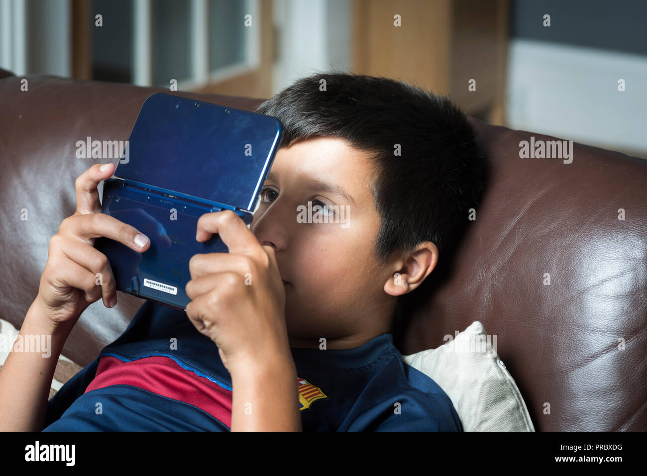 Ocular deviation.Excessive gaming and  electonic gadgets use could make children cross-eyed-boy plays computer game on portable game console Stock Photo