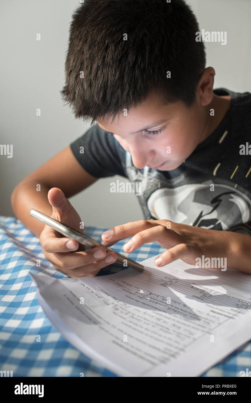 Schoolboy researching homework on smartphone-excessive phone time make children cross-eyed Stock Photo