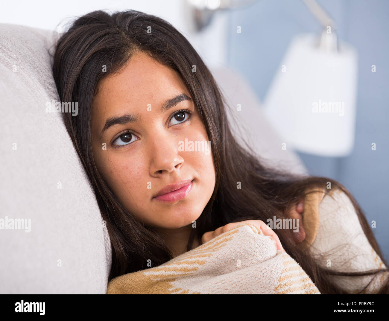 Young sad woman lying on cozy sofa and melancholy at home Stock Photo ...