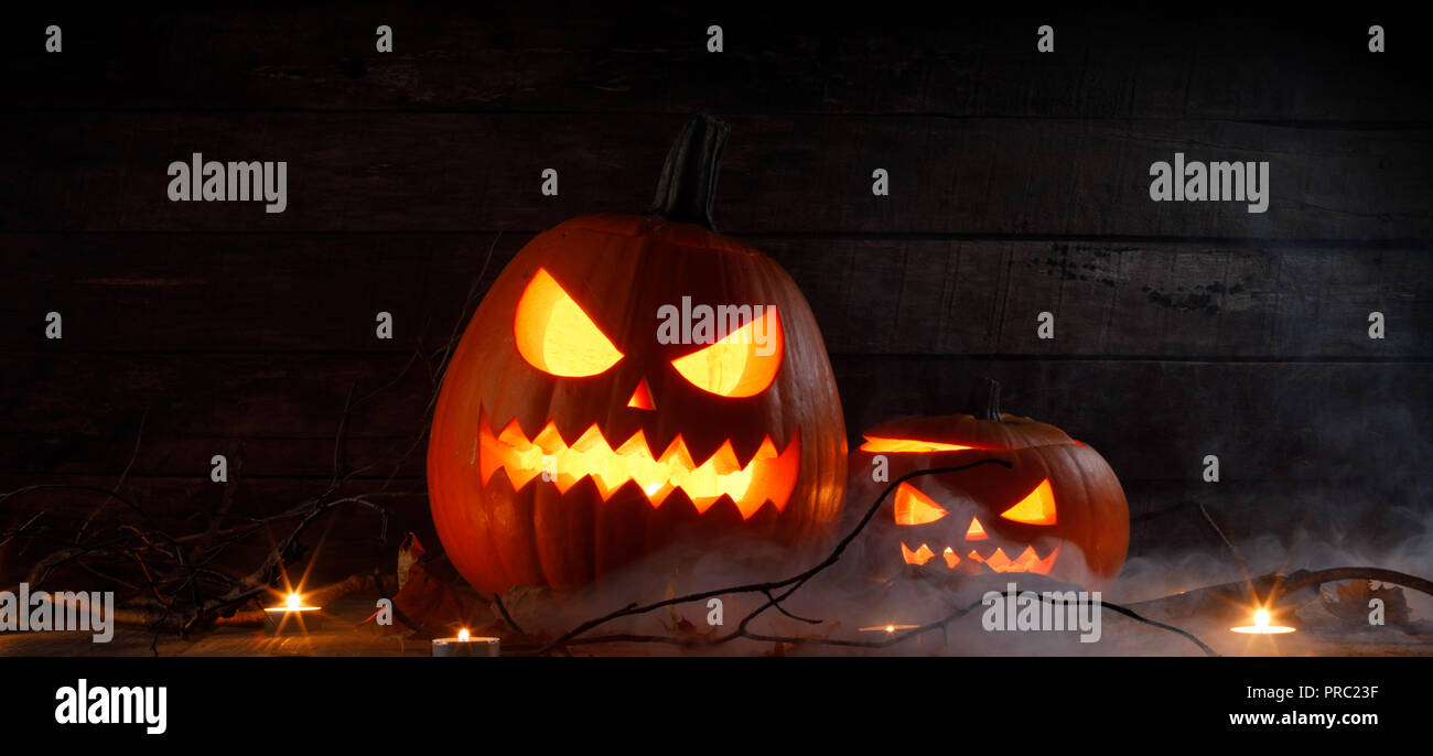Halloween pumpkins head jack o lantern, candles and dry maple leaves in ...
