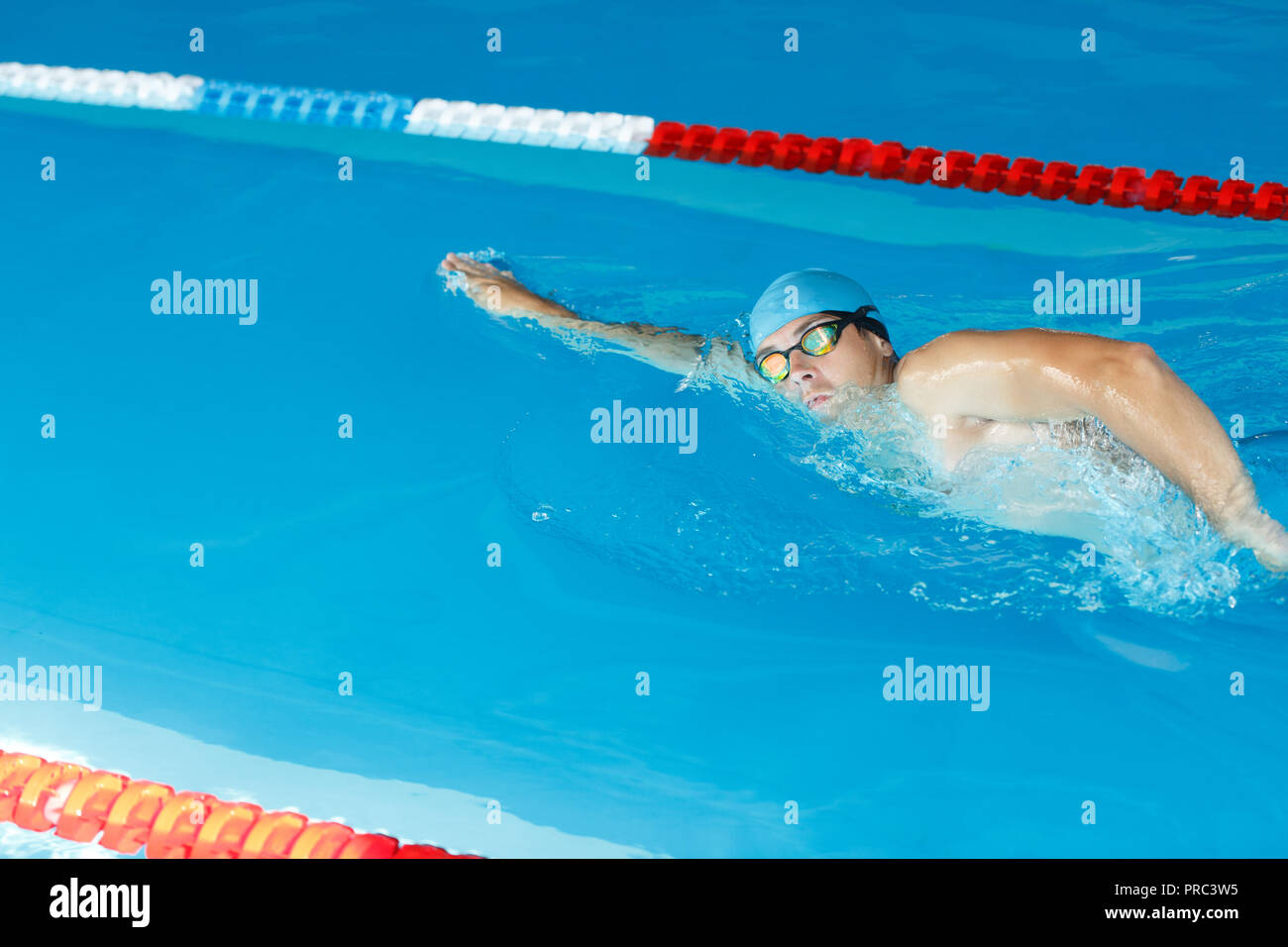 Photo of side of sports man in blue cap swimming under water in pool Stock Photo