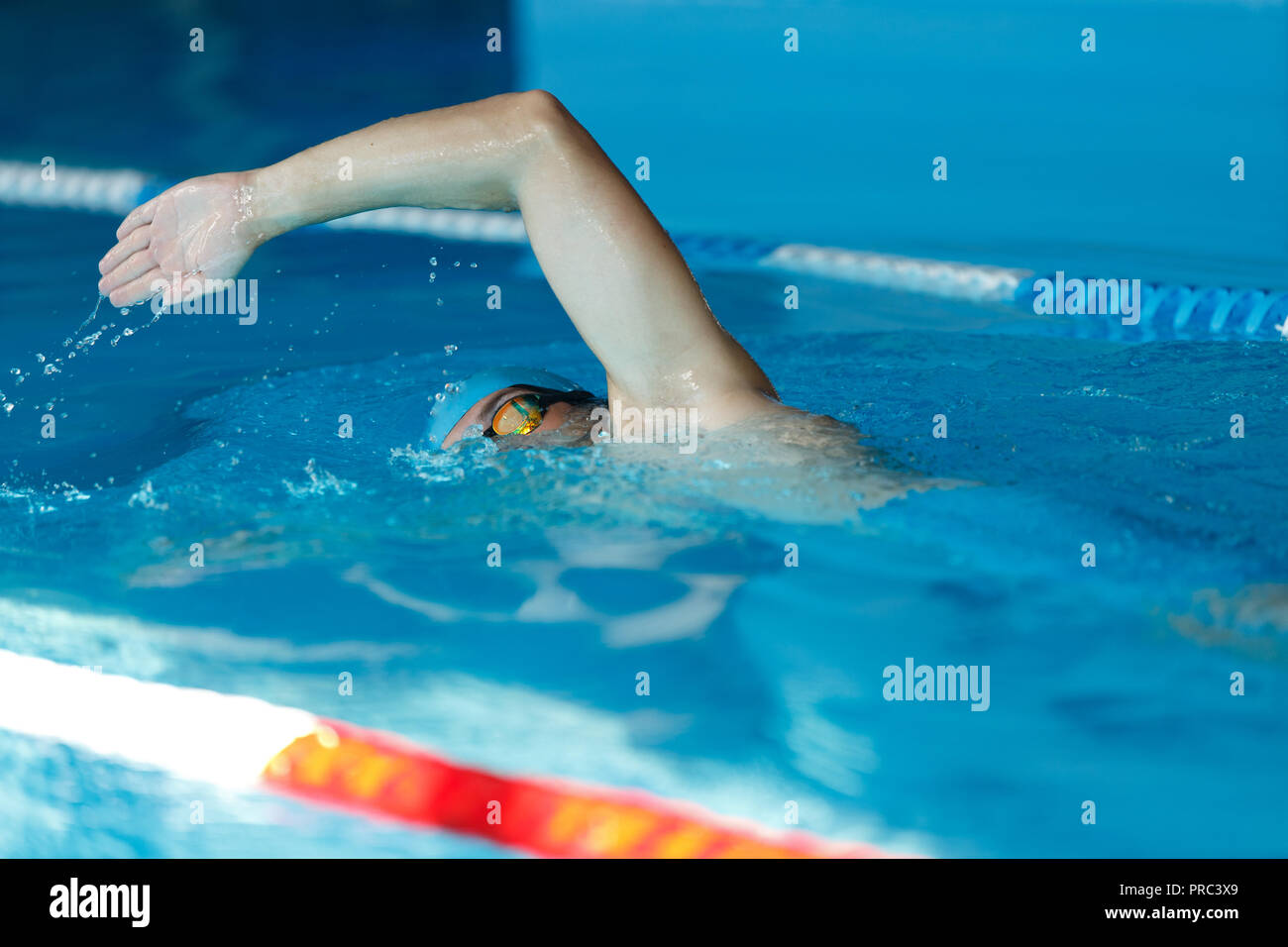 Side view of young sports man in blue cap floating on path in pool Stock Photo