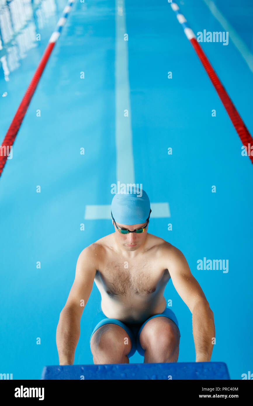 Photo of sportive swimmer man in blue cap at side in swimming pool
