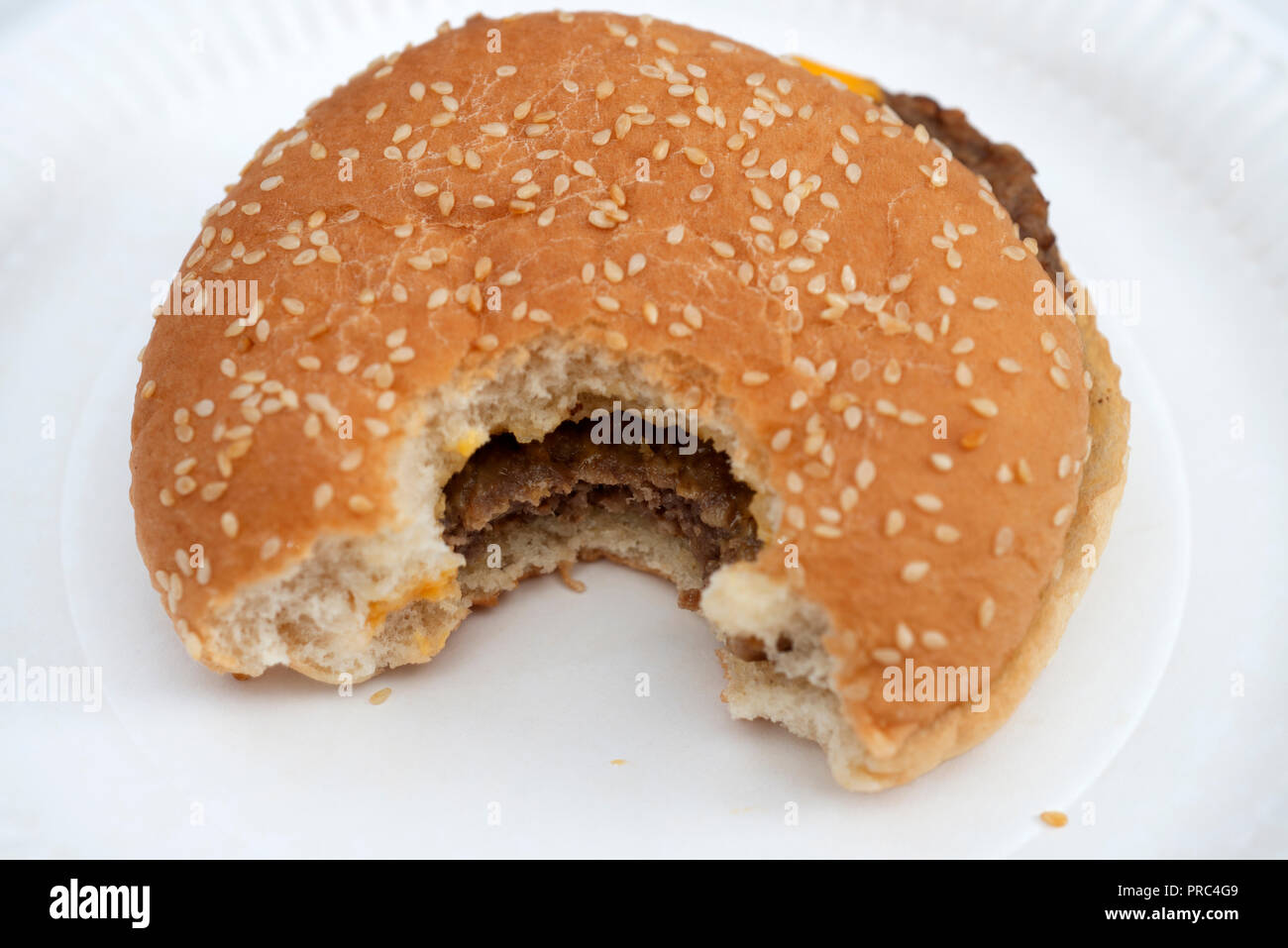 Bite taken out of hamburger in sesame seed bread bun Stock Photo