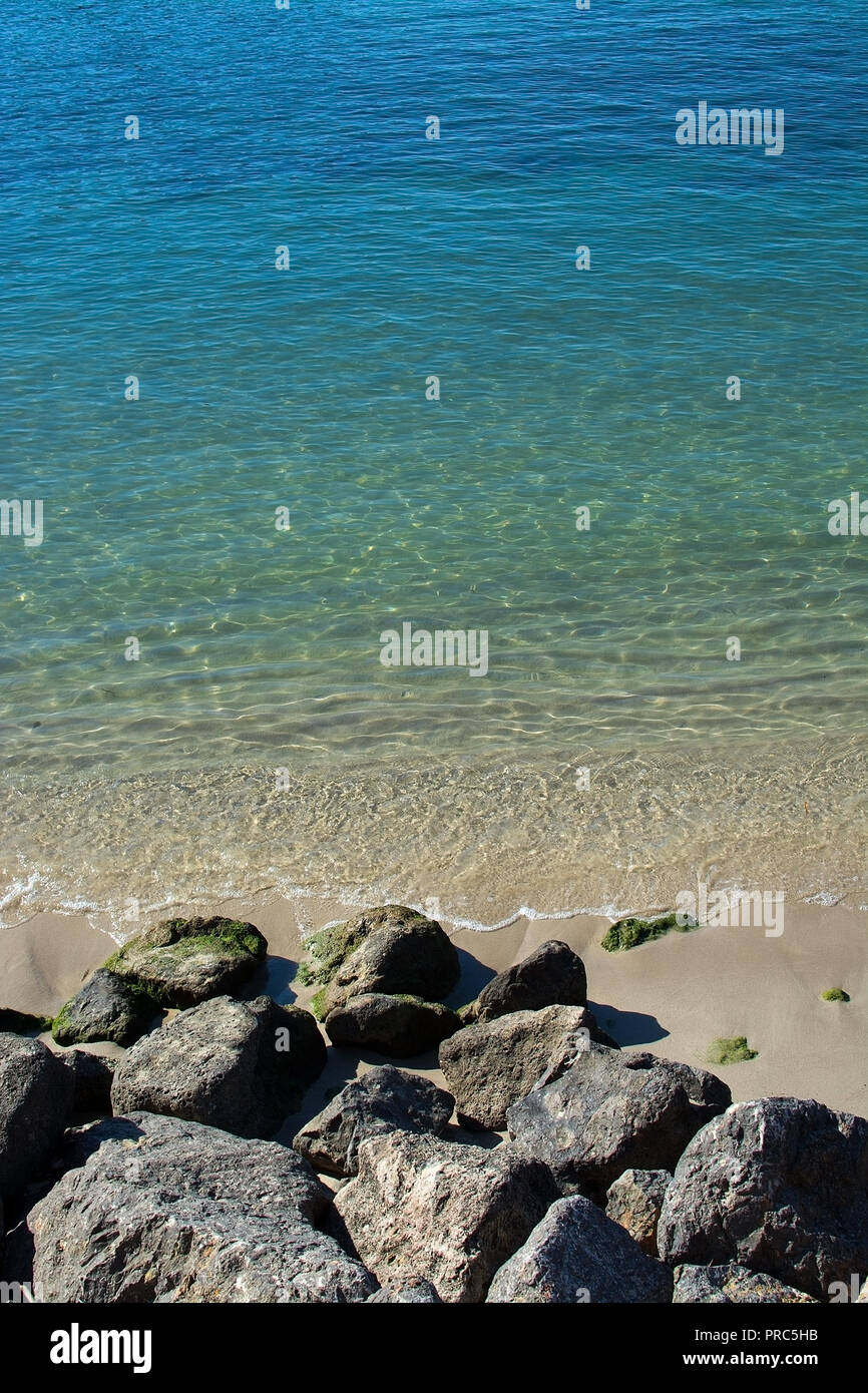 Rocks and shallow sand in ocean water closeup on a sunny afternoon on a sunny day in Mallorca, Spain. Stock Photo