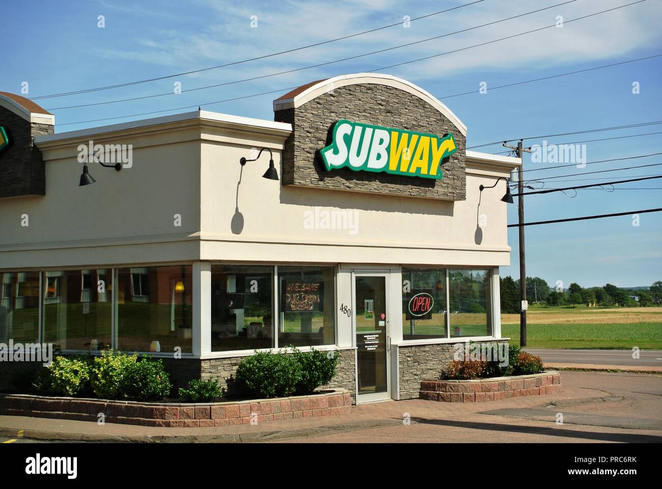 Fast food restaurant Subway with a pretty white, yellow and green logo sign on a gray brick background on a sunny day at Charlottetown, PEI, Canada Stock Photo