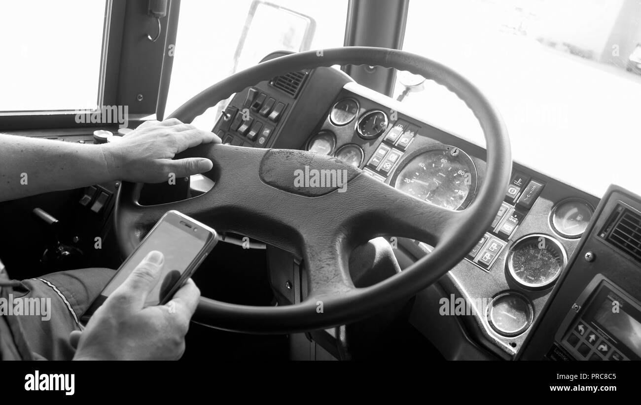 Black and white photo of bus driver using smartphone while driving Stock Photo
