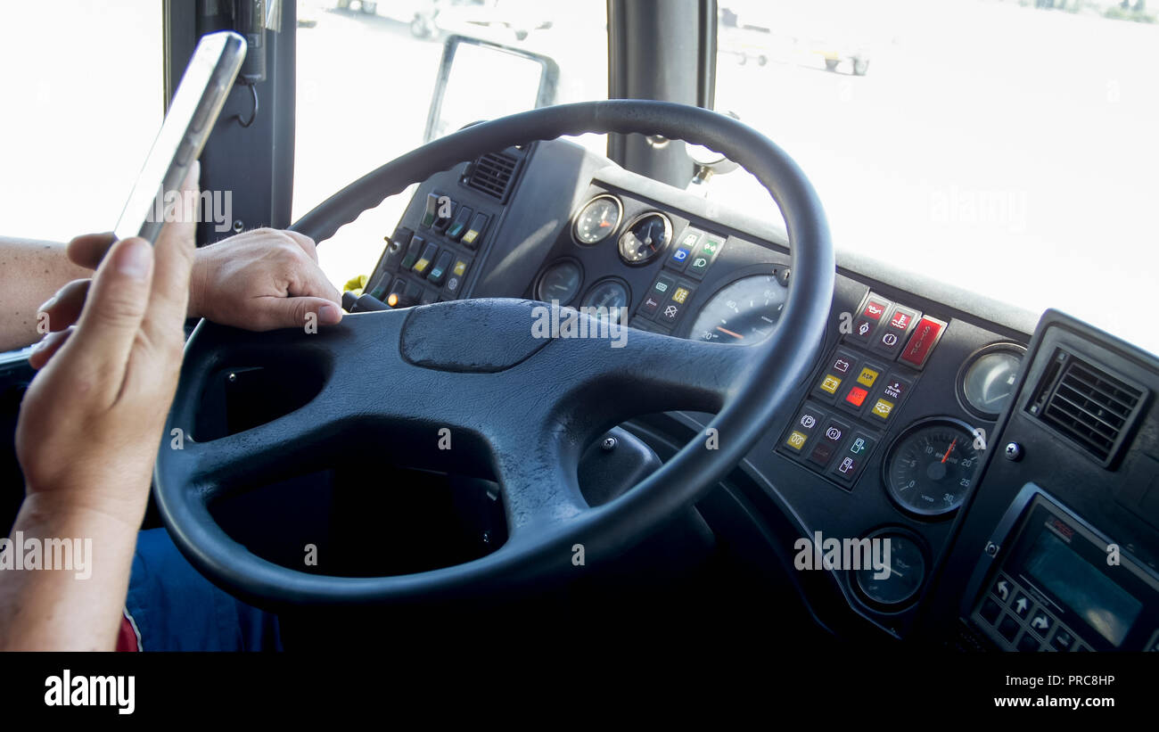 Closeup image of irresponsible driver with smartphone while driving public bus. Danger in transport. Irresponsible driver Stock Photo