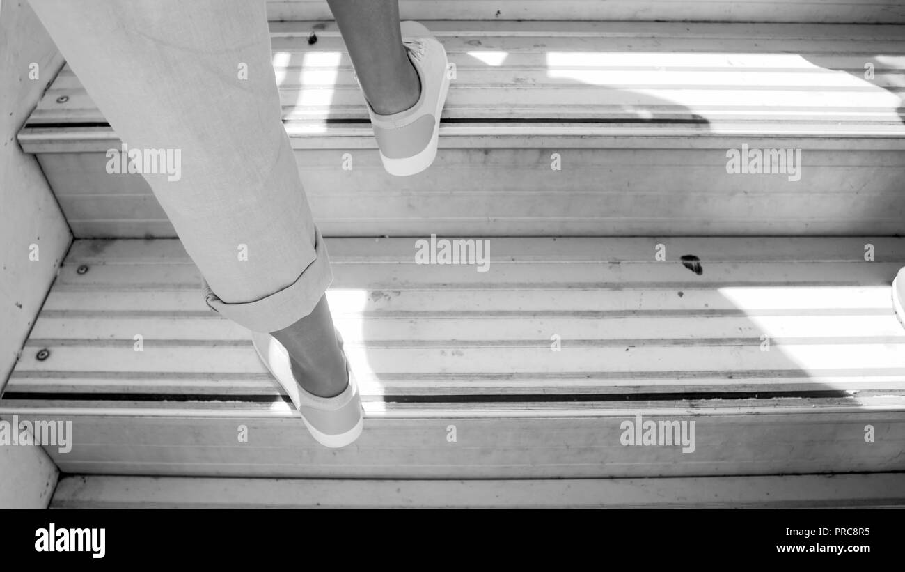Black and white photo of female feet on airplane doard stairs Stock Photo