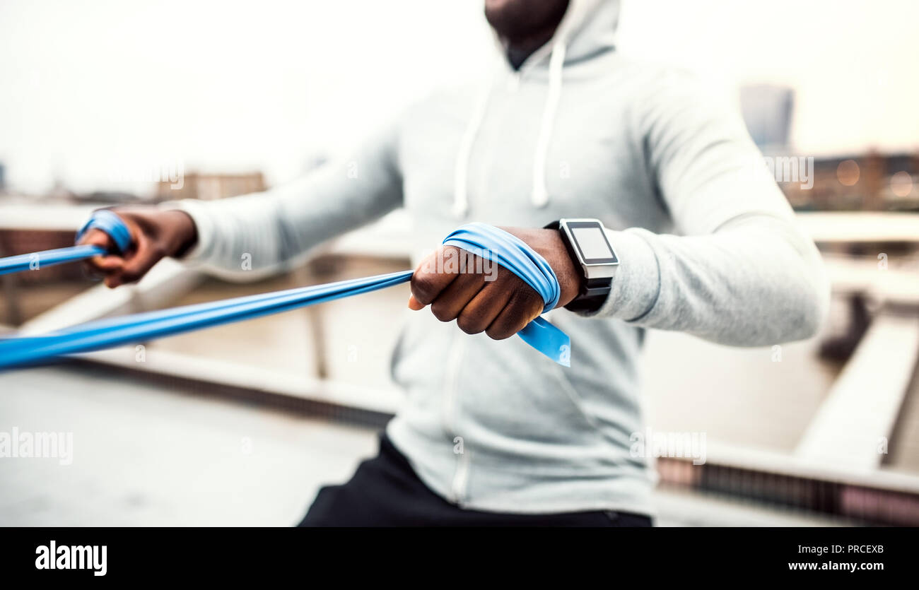 Young black sportsman exercising with elastic rubber bands in London. Stock Photo