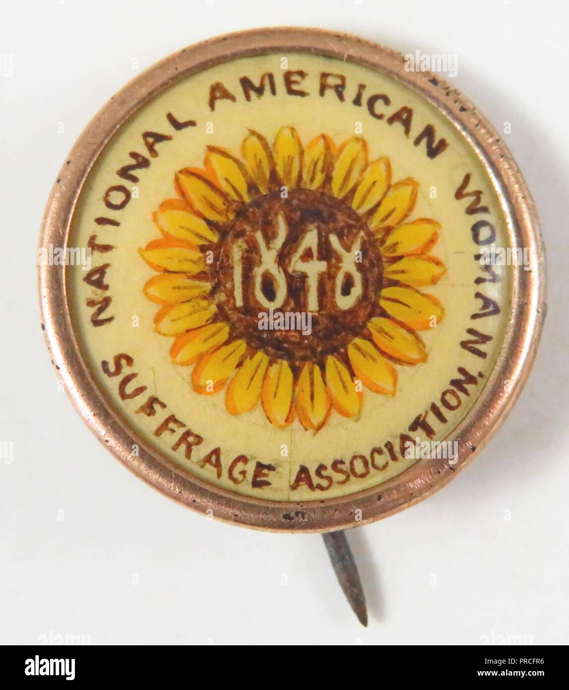 Yellow, brown, and cream suffrage pin, with the year '1848' (commemorating the date of the Seneca Falls Convention) inscribed to the center of a Kansas sunflower, and the text 'National American Woman Suffrage Association, ' manufactured for the American market by the National American Woman Suffrage Association, 1896. Photography by Emilia van Beugen. () Stock Photo