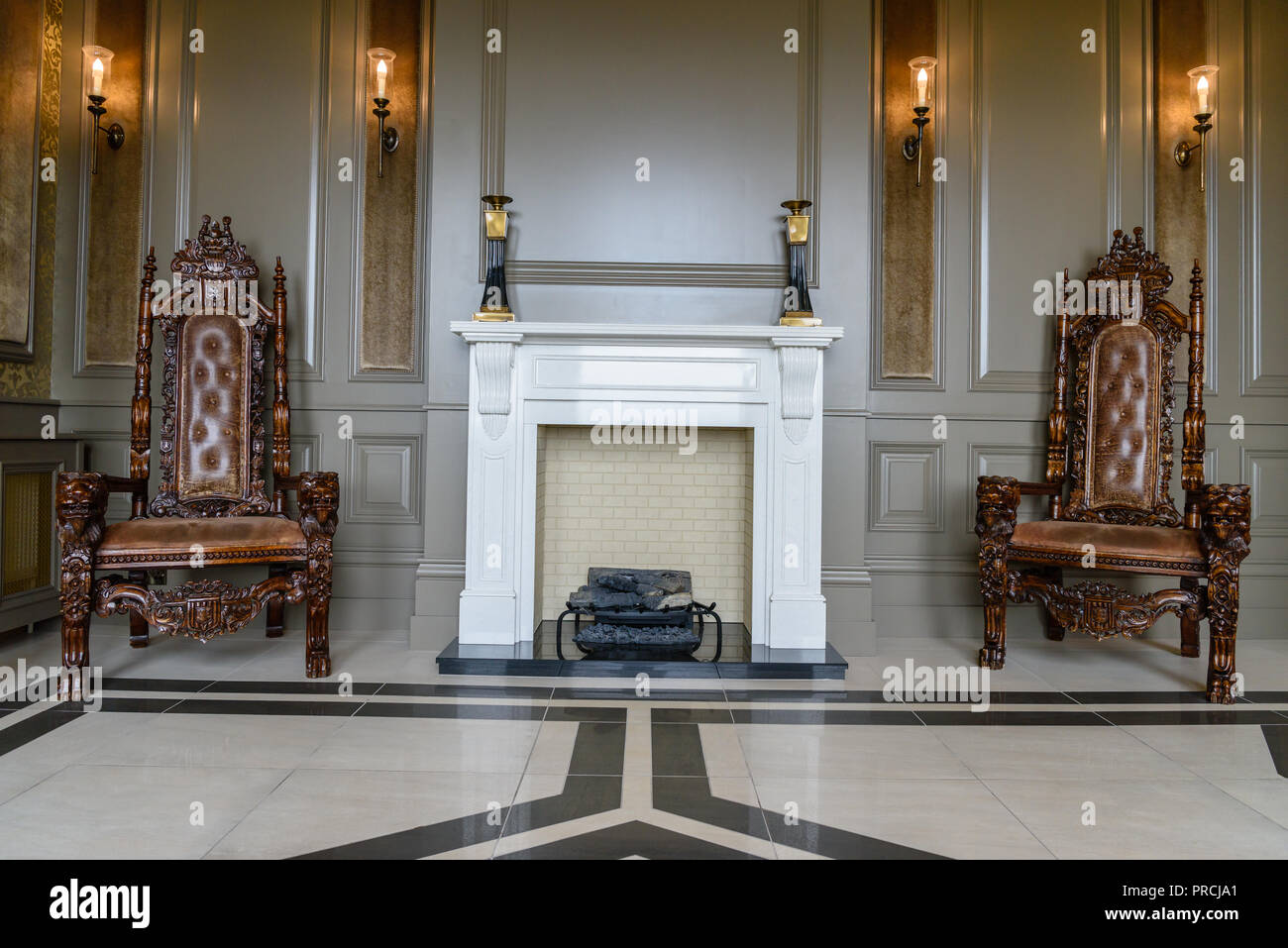 Fireplace and ornate wood and leather chairs in a stately home country house. Stock Photo