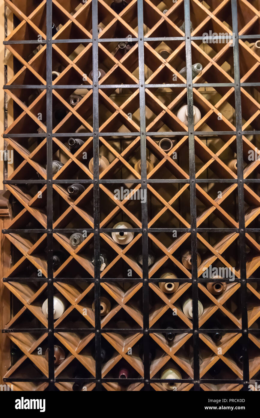 Wine bottles behind a metal security screen in the wine cellar of a house. Stock Photo
