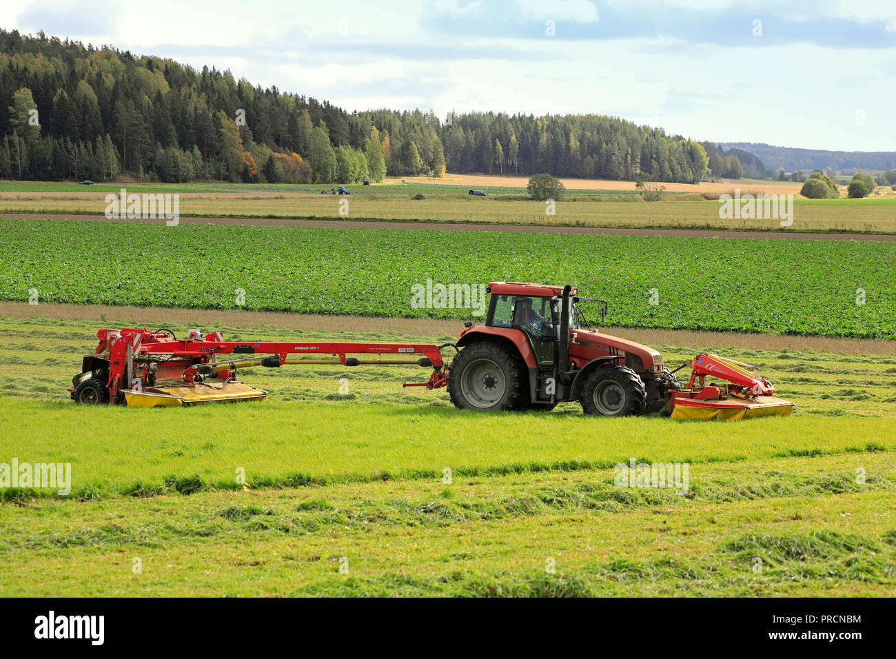 Salo, Finland - September 23, 2018: Farmer cuts hay on farmland with NOVACAT T trailed disc mower pulled by Case IH CS120 tractor on a beautiful day. Stock Photo