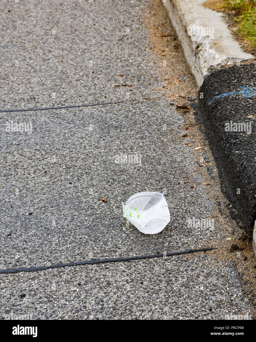 An empty discarded clear plastic cup lying in the street or gutter in Speculator, NY USA, litter concept. Stock Photo