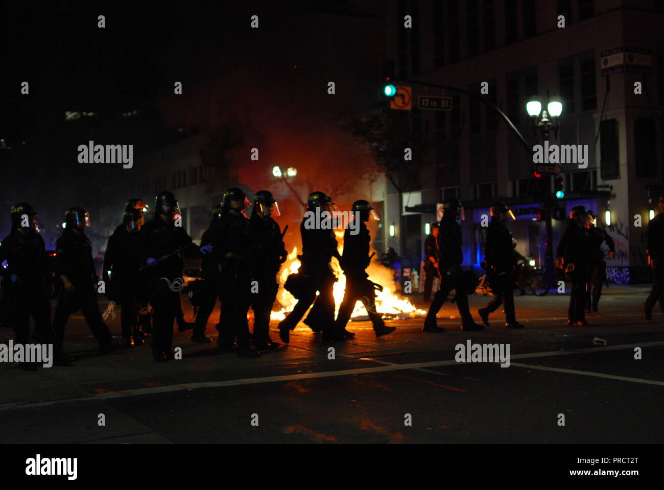 Oakland police officers march in front of a fire burning on Broadway during protests against the election of President Donald Trump on Nov. 9, 2016. Stock Photo