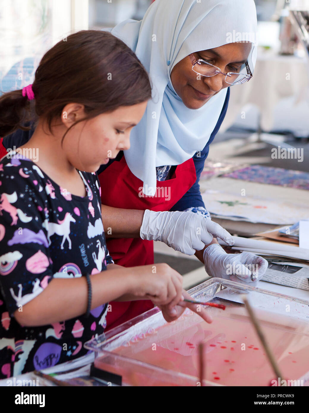 Muslim woman helping schoolgirl with art project - USA Stock Photo