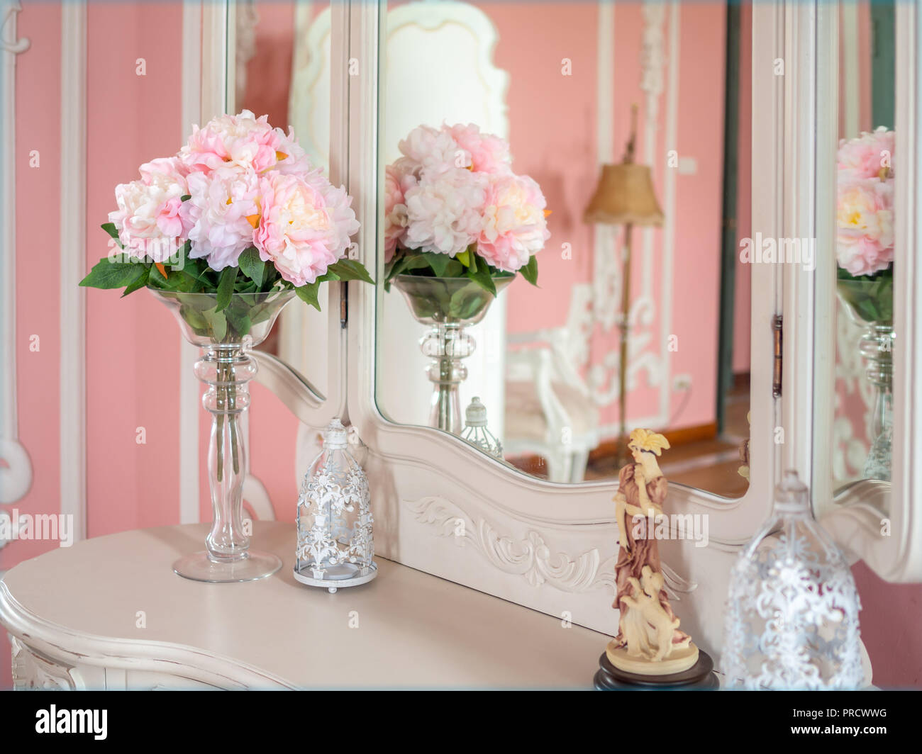 Bouquet of pink flowers in glass vase on white boudoir table and sweet pink room. Vintage decoration style. Stock Photo