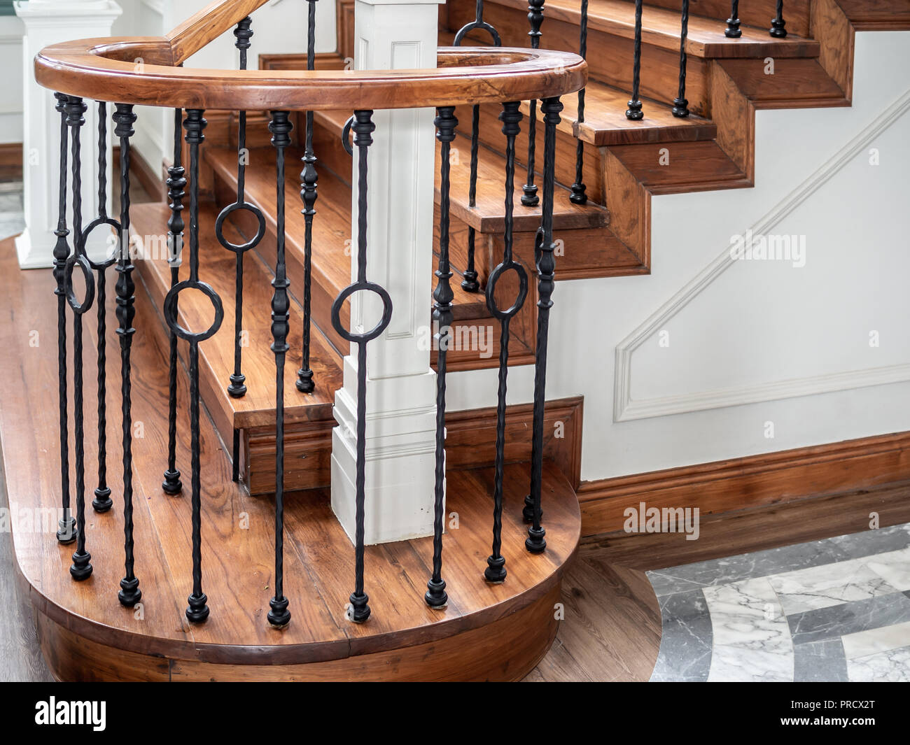 Classic vintage elegant wooden staircase with wrought iron railing. Stock Photo
