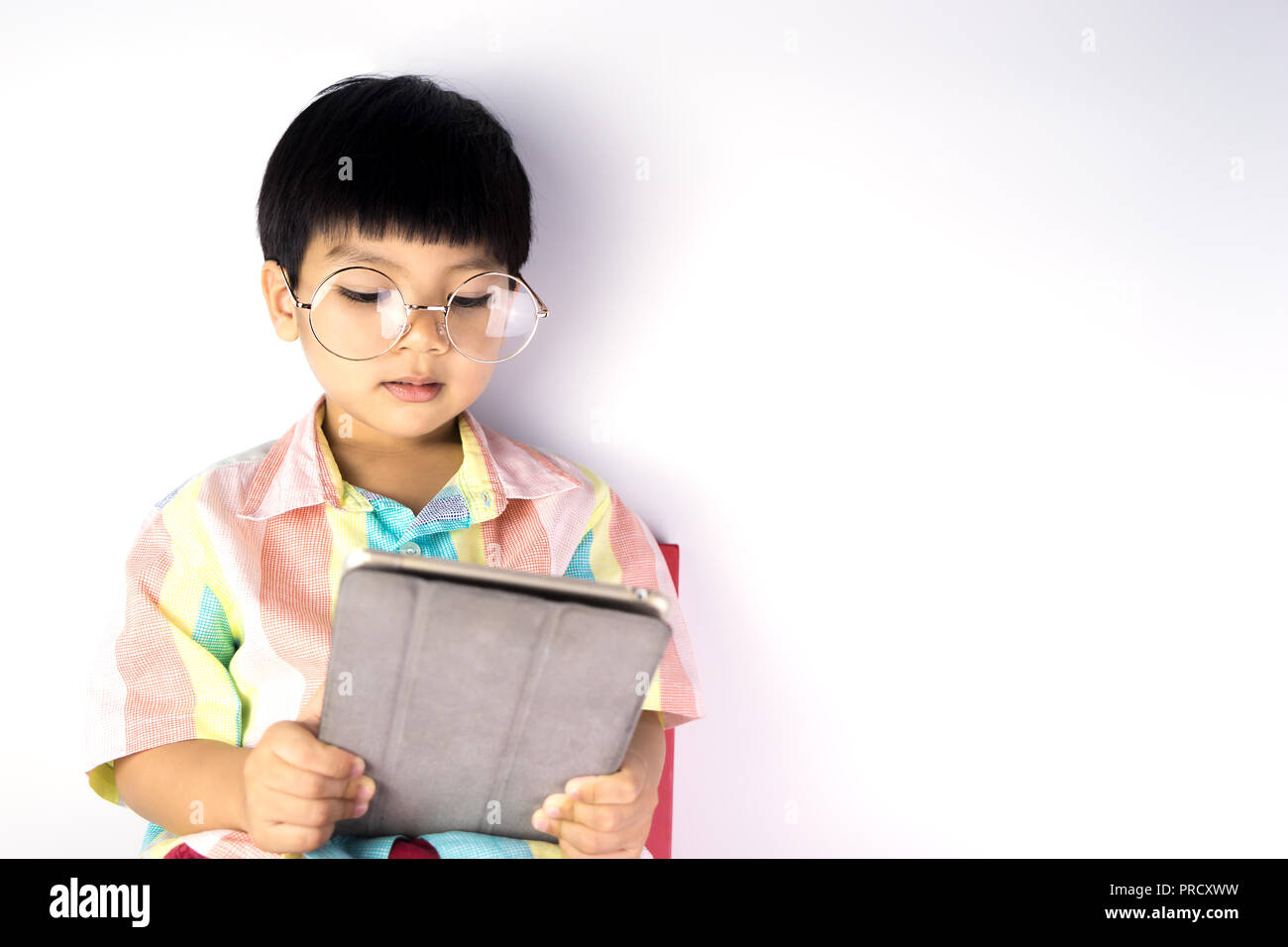 Nerdy Asian boy is reading on tablet isolated Stock Photo