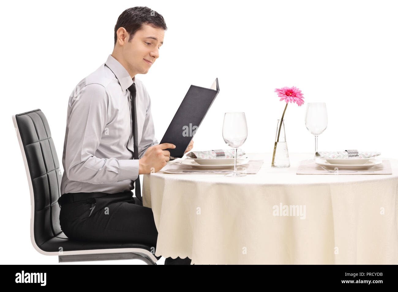 Young guy at a restaurant table reading the menu isolated on white background Stock Photo