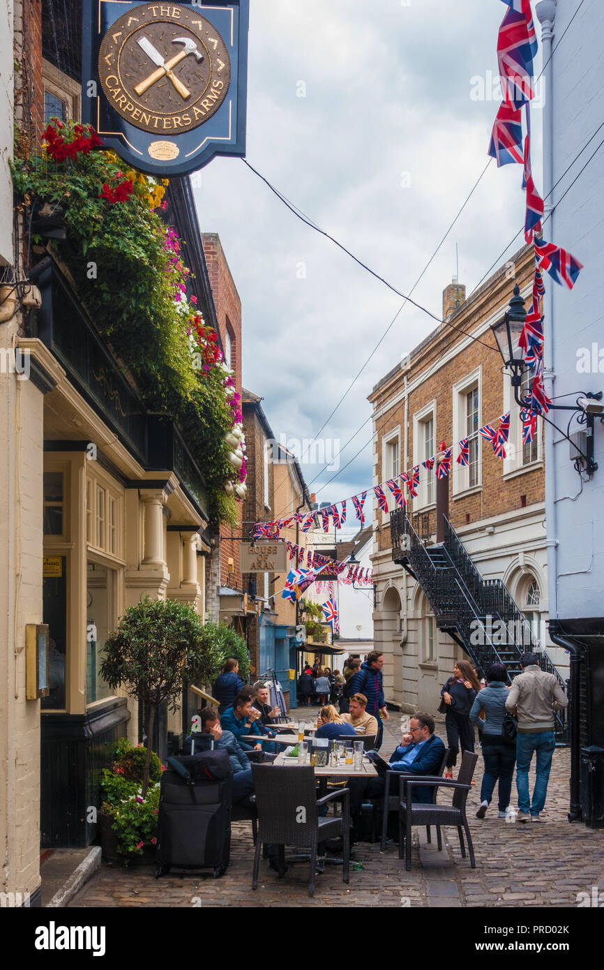 People sit at tables and chairs outside The Carpenters Arms pub in Market Street, Windsor, UK. Stock Photo