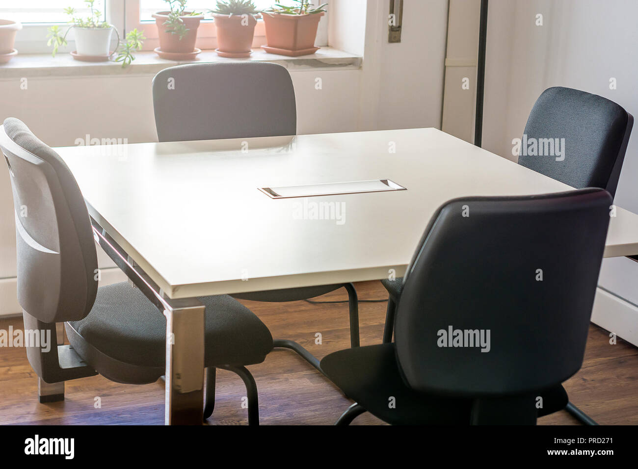 four empty chairs in a conference room with a white table Stock Photo