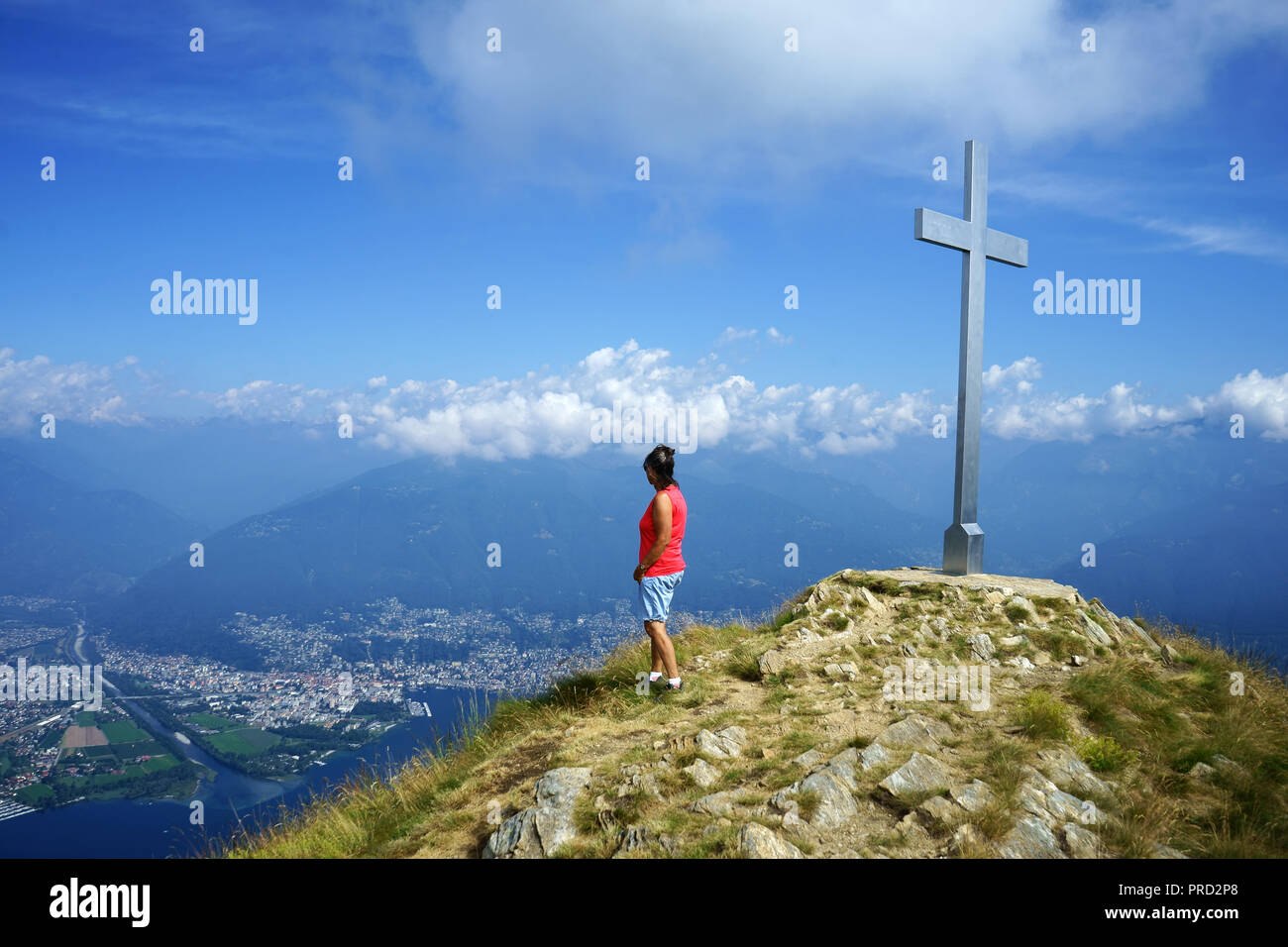 Hiker on summit of Monte Gambarogno, view toward Locarno, delta of Maggia river lake lago Maggiore, Ticino, Switzerland Stock Photo