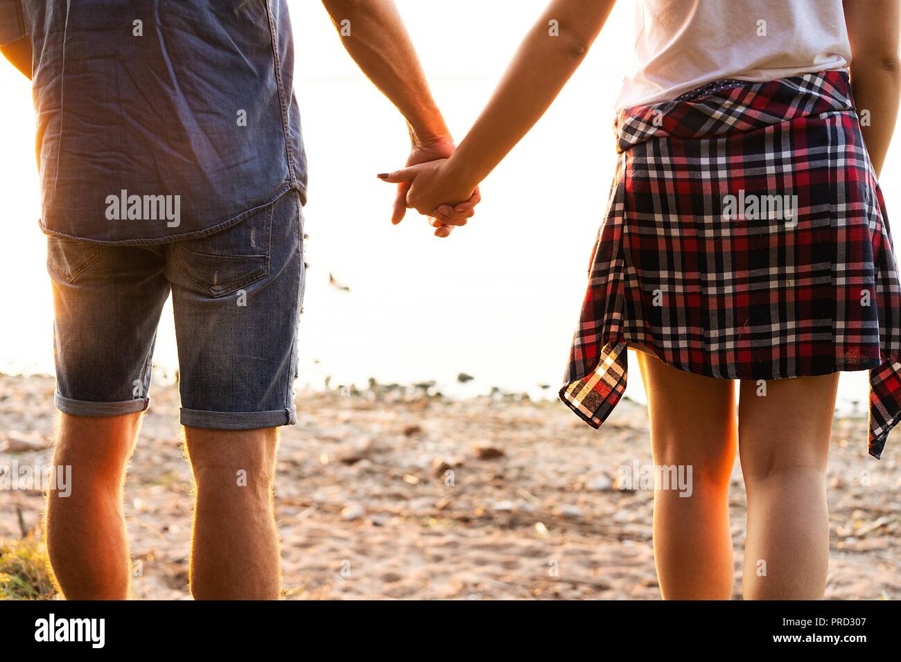 Young couple in love walking in the autumn park holding hands looking in the sunset Stock Photo