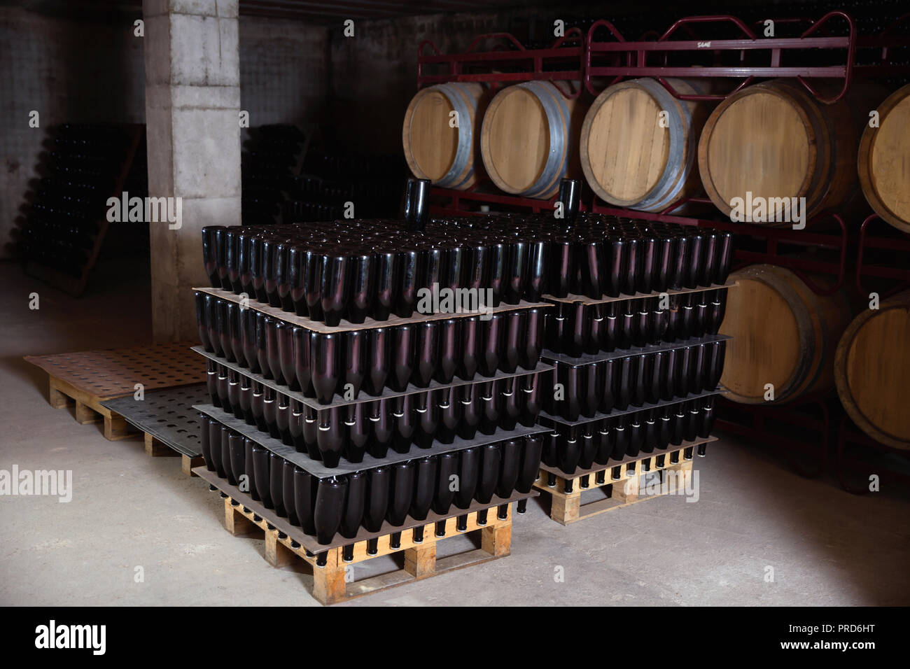 Pallets of wine bottles and wooden wine barrels in vinery vault Stock Photo