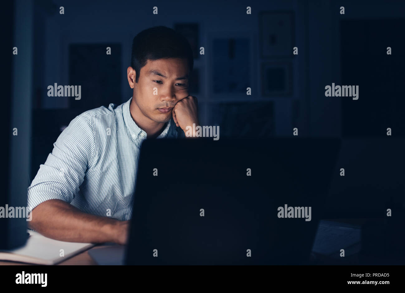 Tired Asian businessman working on a laptop late at night Stock Photo