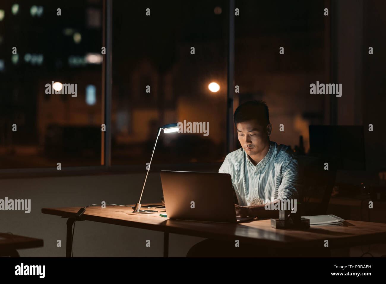 Asian businessman working alone in a dark office at night Stock Photo