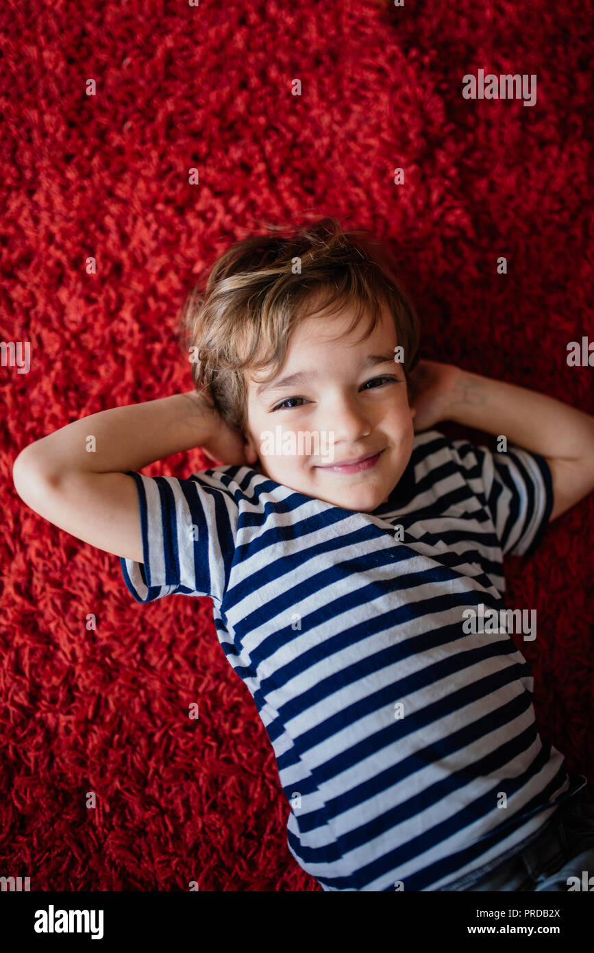 Little boy lying on a red carpet Stock Photo