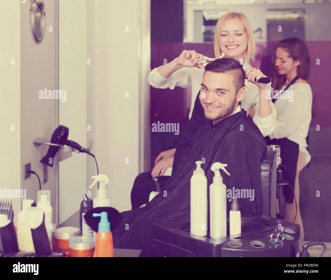 Positive Young Guy Cuts Hair At The Hair Salon Focus On The Man