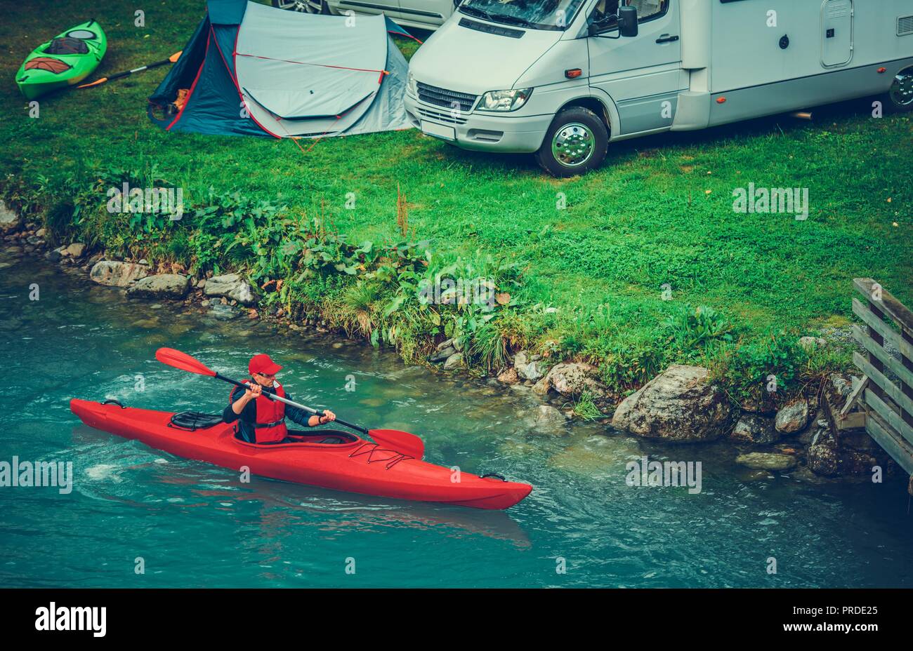 Waterfront RV and Tent Camping with Kayaking. Caucasian Sportsman in the Kayak on Glacial Lake. Stock Photo