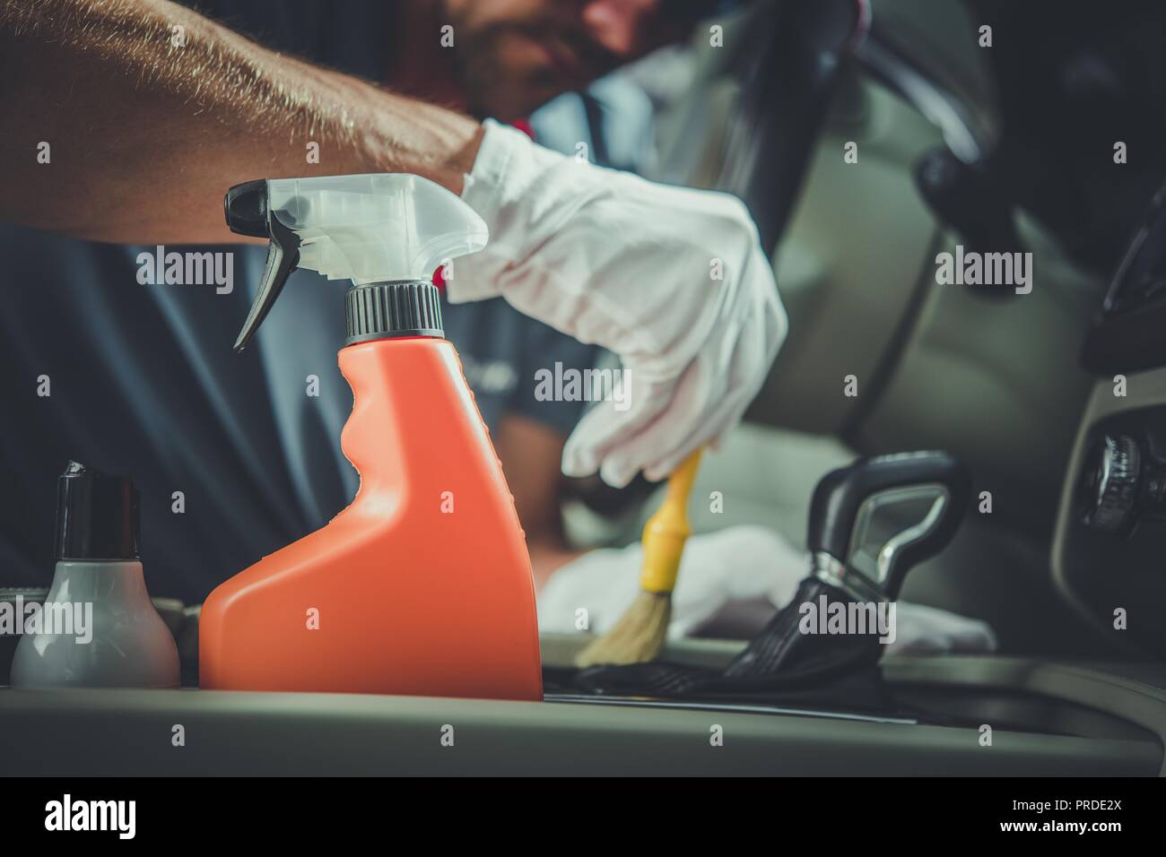 Car Care Cleaning Product. Detergent Bottle and Caucasian Worker Detailing Vehicle. Stock Photo