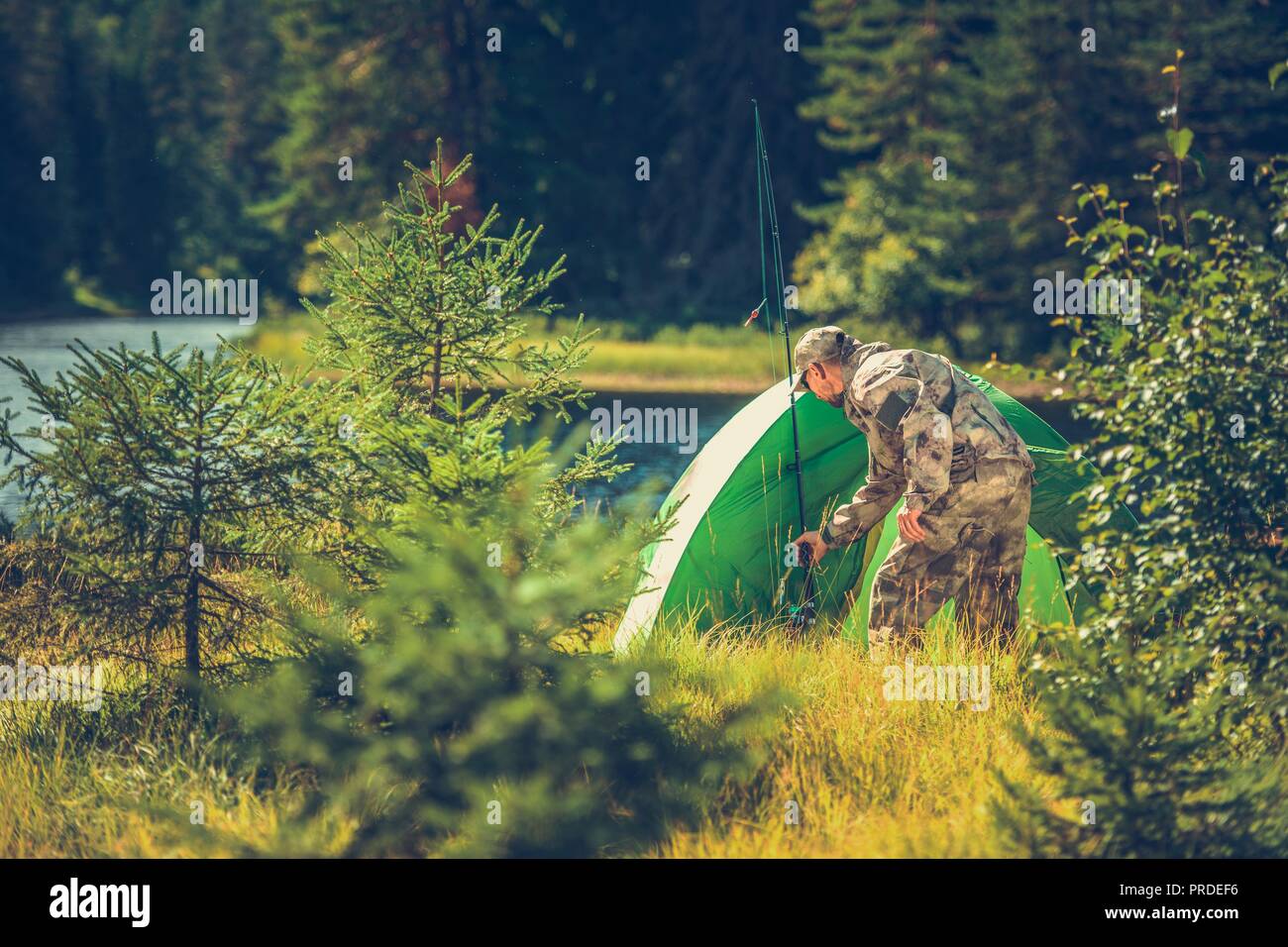 Summer Hunters Camping in the Wild. Campsite and the Fishing Rod. Caucasian Men in the Survival Mode. Stock Photo