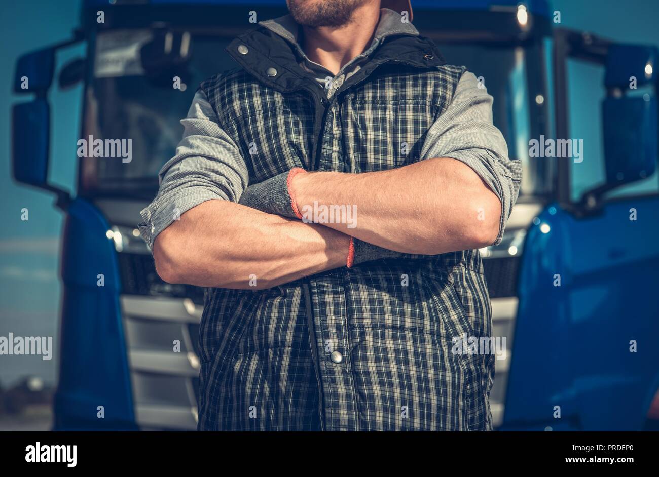 Truck Driver Workhorse. Caucasian Men in Front of His Vehicle with Crossing Arms. Powerful Transportation Industry Concept. Stock Photo