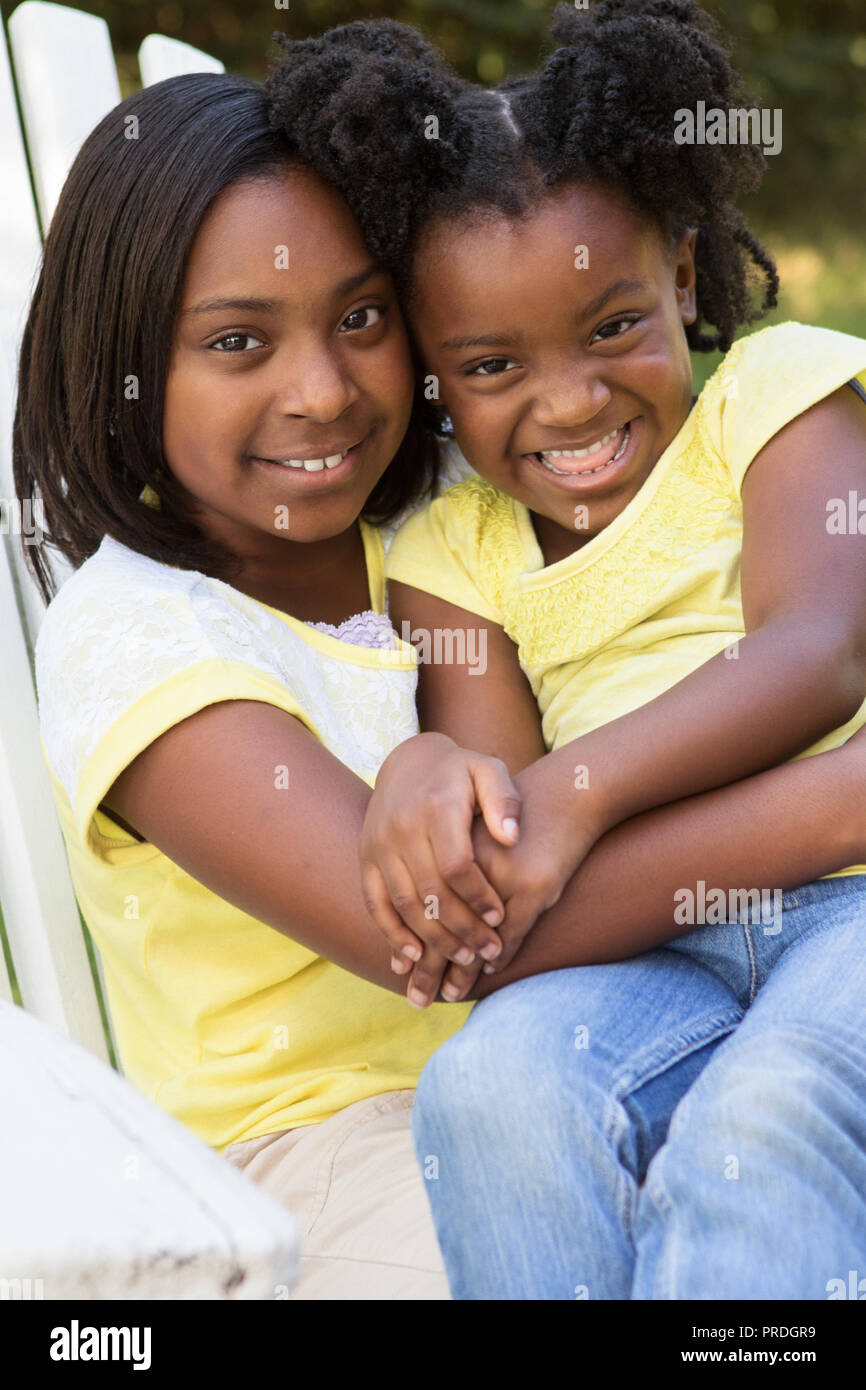 Portrait of two African American sisters hugging outside. Stock Photo