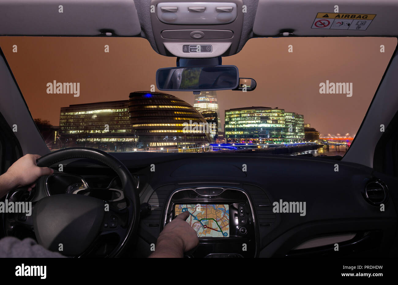 Driving a car while using the touch screen of a GPS navigation system during a foggy night in London City, UK Stock Photo