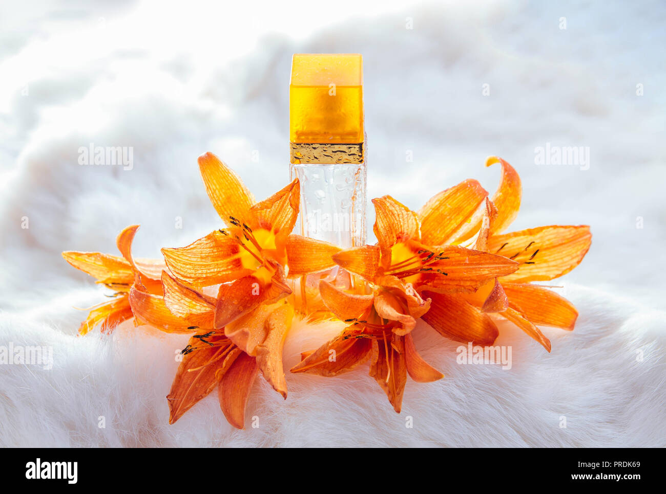 Bottle of perfume with lily on white fur background Stock Photo